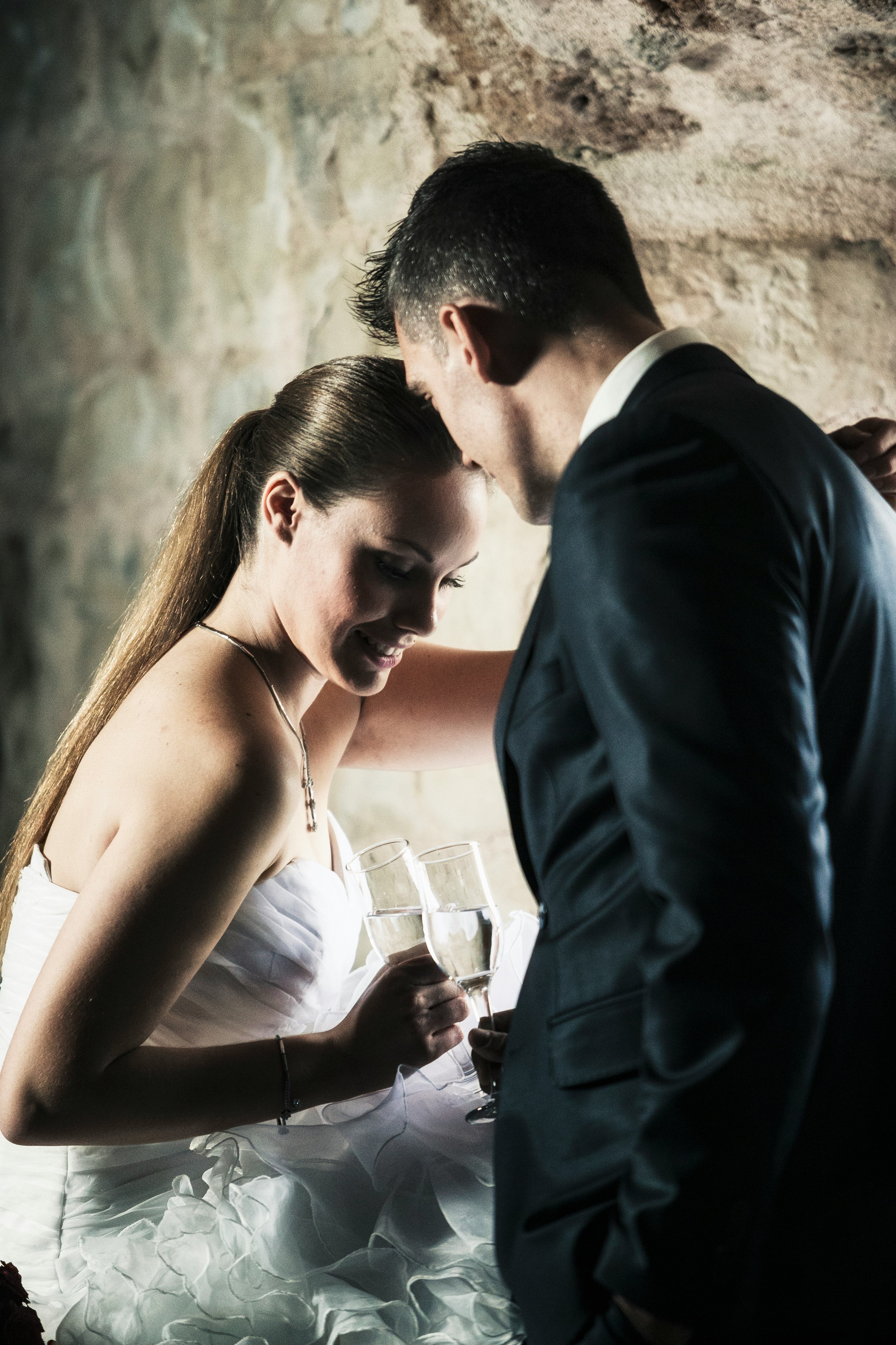 man in black suit jacket holding woman in white spaghetti strap top